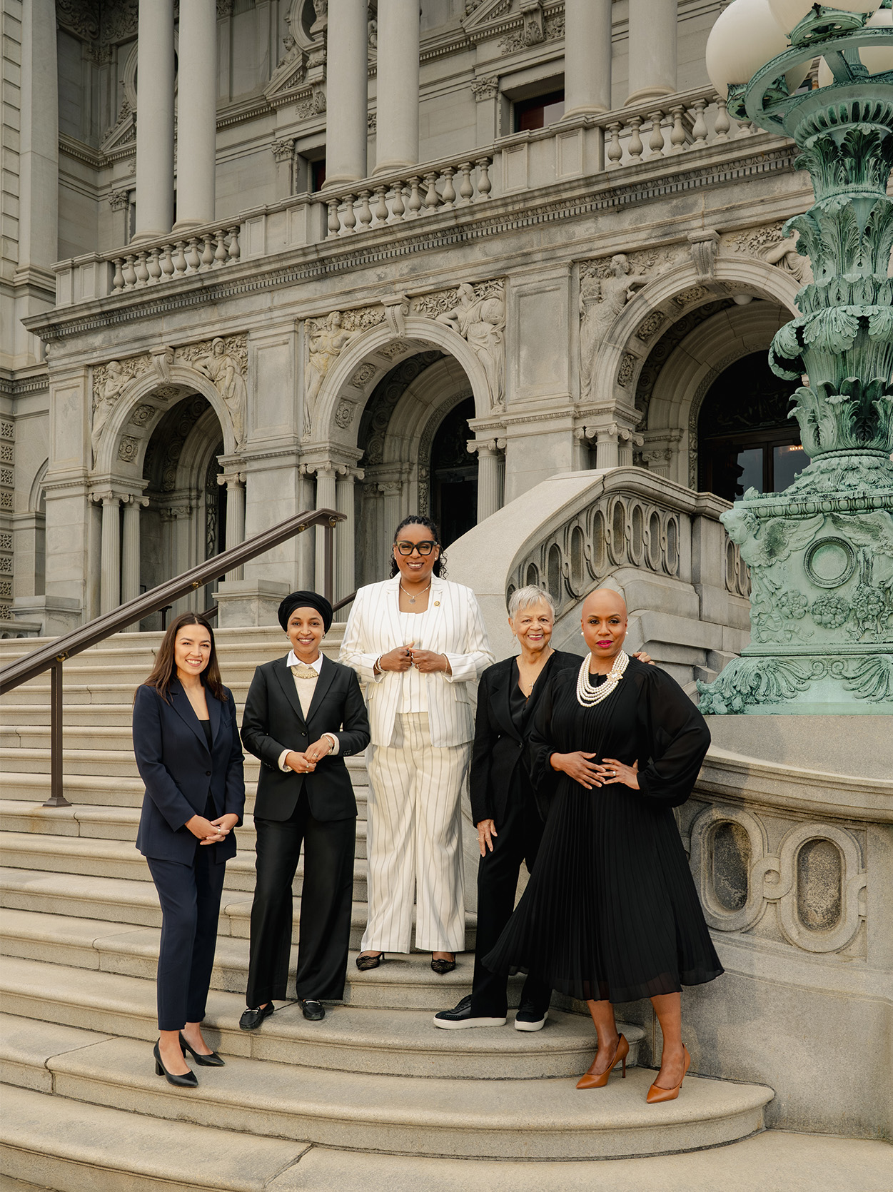 Five congresswomen stand on the Library of Congress steps beside a green patina lamp post. From left: Alexandria Ocasio-Cortez, Ilhan Omar, LaMonica McIver, Bonnie Watson Coleman, and Ayanna Pressley.