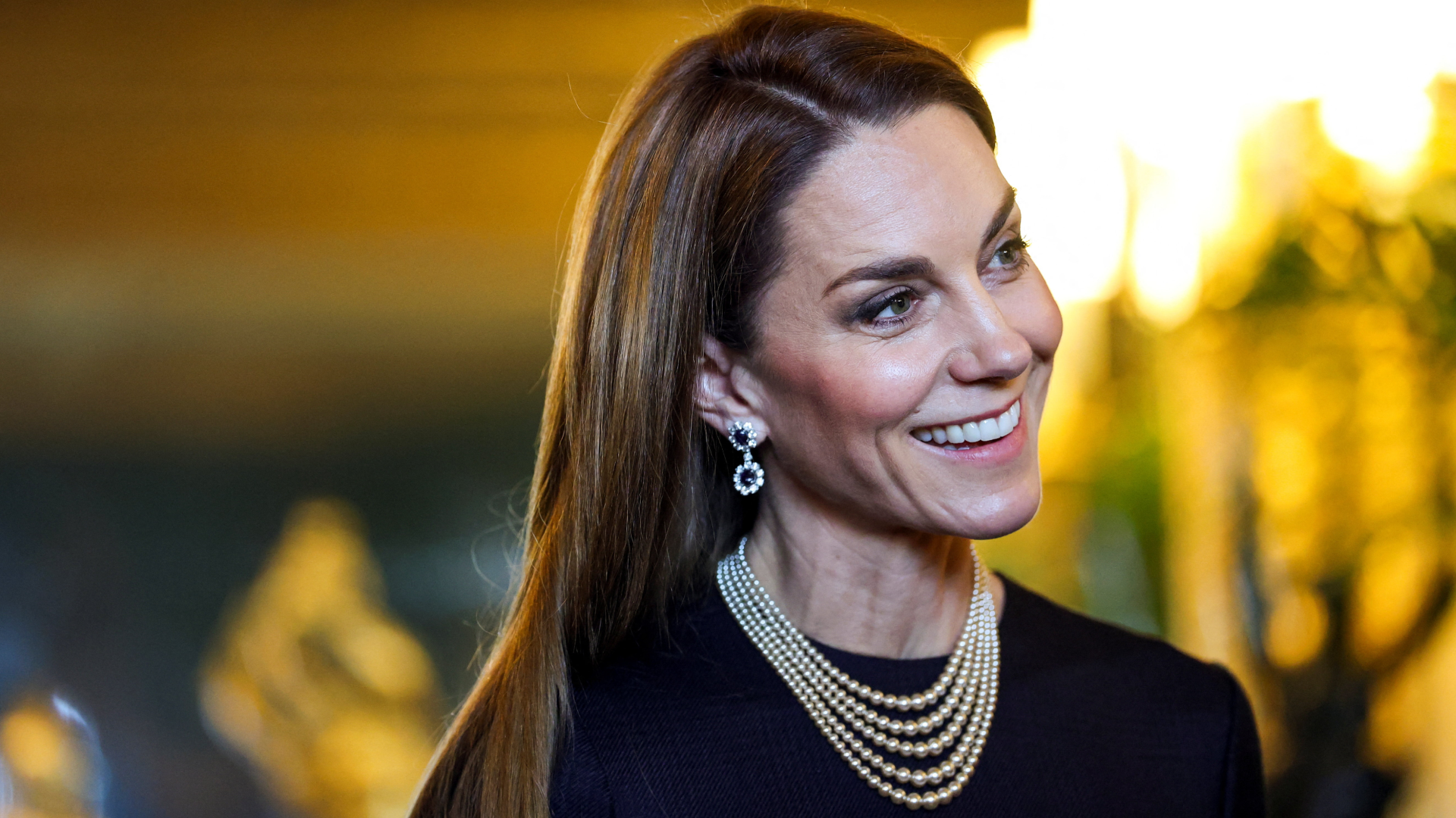 Princess Kate wearing a navy dress and pearls, smiling