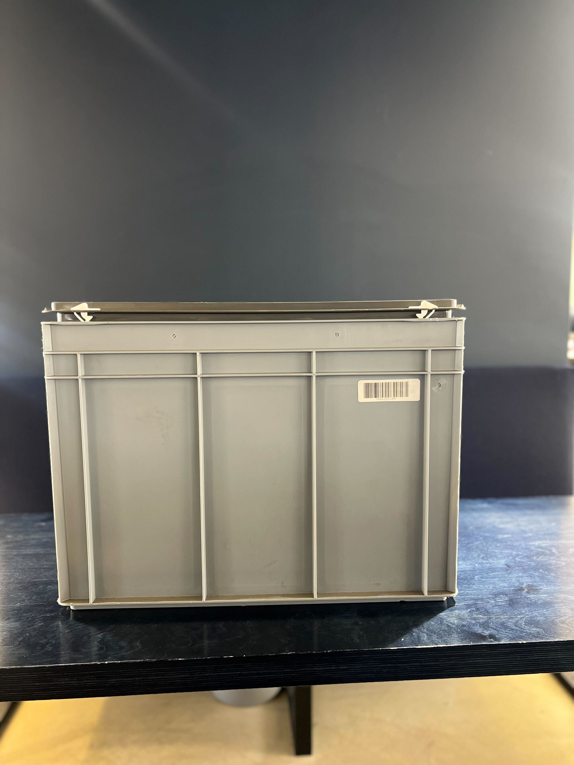 A light gray crate on a black table in a gray room.