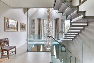 landing with modern staircase, hanging pendant, stone flooring, artwork on the walls