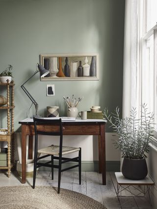 A light sage green office space with a wooden desk