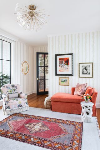bedroom sitting room suite with coral chaise longue and floral armchair and striped wallcovering