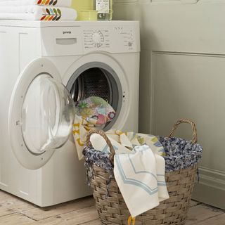 white washing machine and bucket with cloths