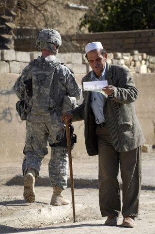 An Iraqi citizen reads a leaflet handed to him by an Iraqi National Policeman during a joint U.S. Army Iraqi police walking patrol through the Rashid community in Bahgdad.