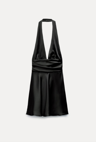 a black halter dress from Zara in front of a plain backdrop