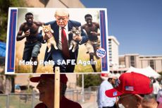 A man carries an AI-generated image of former US President and Republican presidential candidate Donald Trump carrying cats away from Haitian immigrants, a reference to falsehoods spread about Springfield, Ohio, during a campaign rally for Trump at the Tucson Music Hall in Tucson, Arizona, September 12, 2024. 