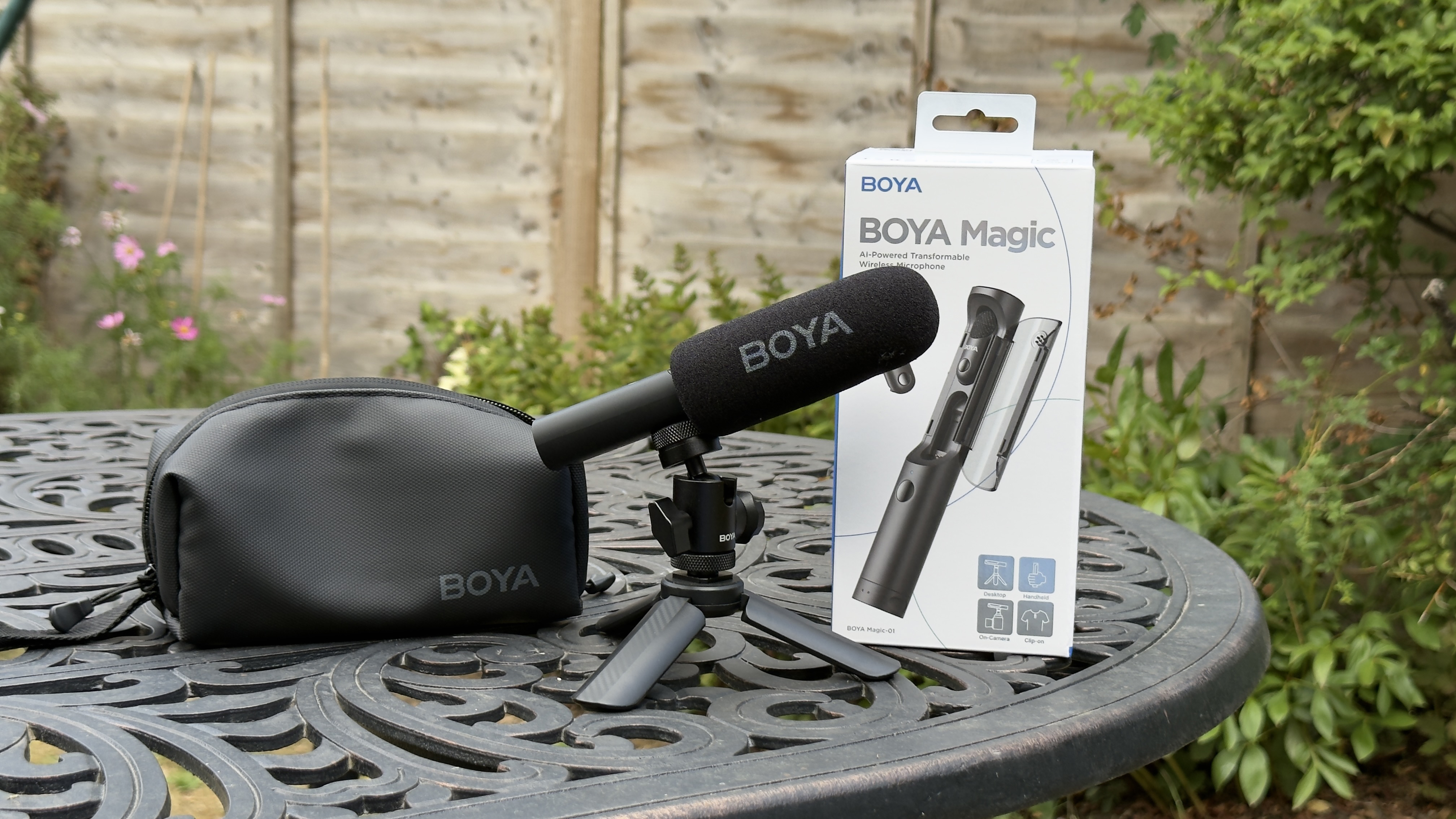 Shot of the Boya Magic’s gun mic configuration on a mini tripod sitting on a desktop adjacent to a laptop.