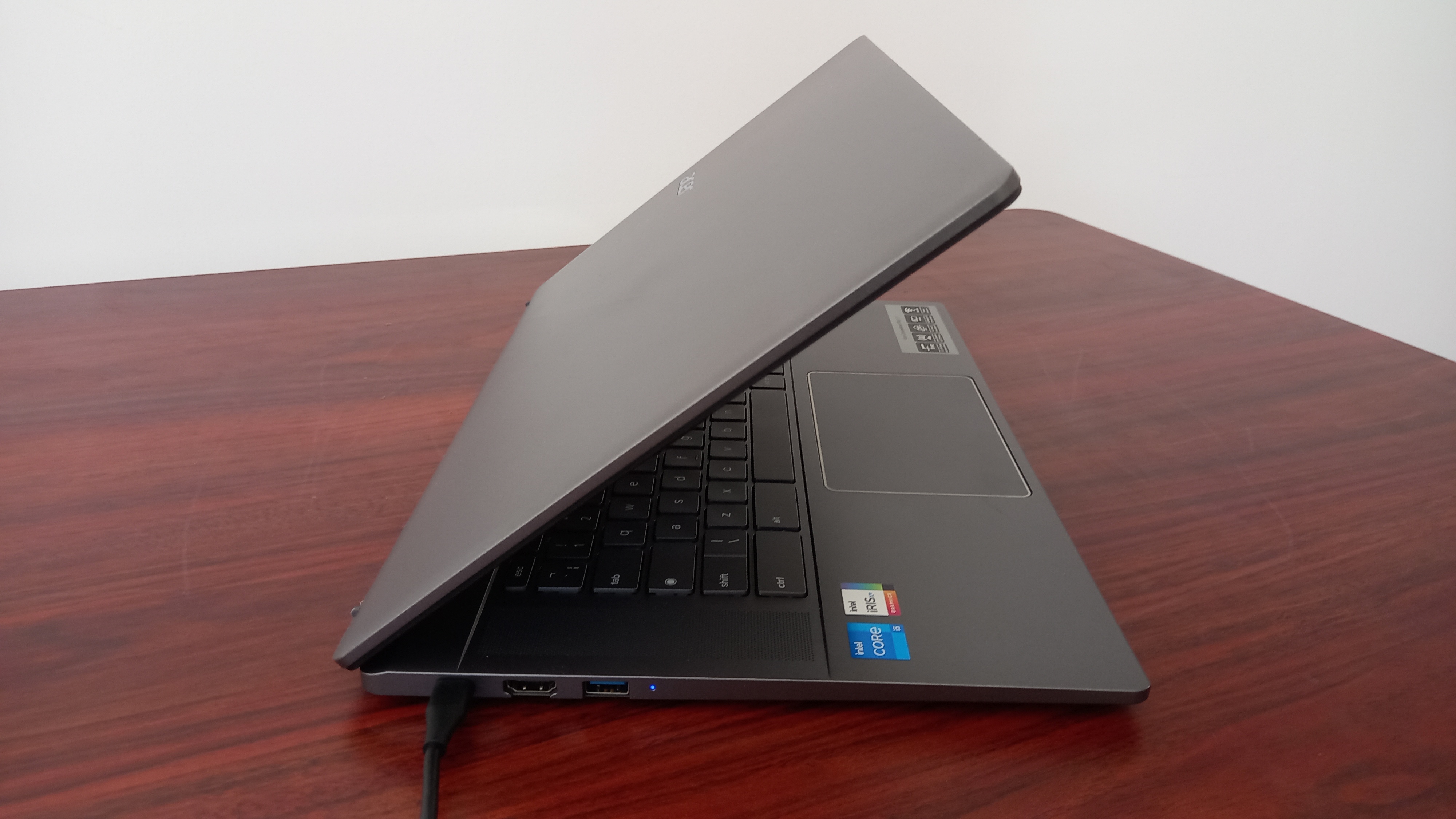 An Acer Chromebook Plus 515 on desk showing abstract painted wallpaper on its screen