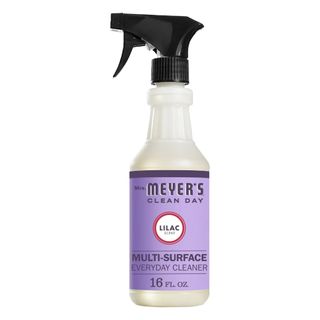 A clear bottle of Mrs. Meyers multi-surface spray with a purple label and black spray lid