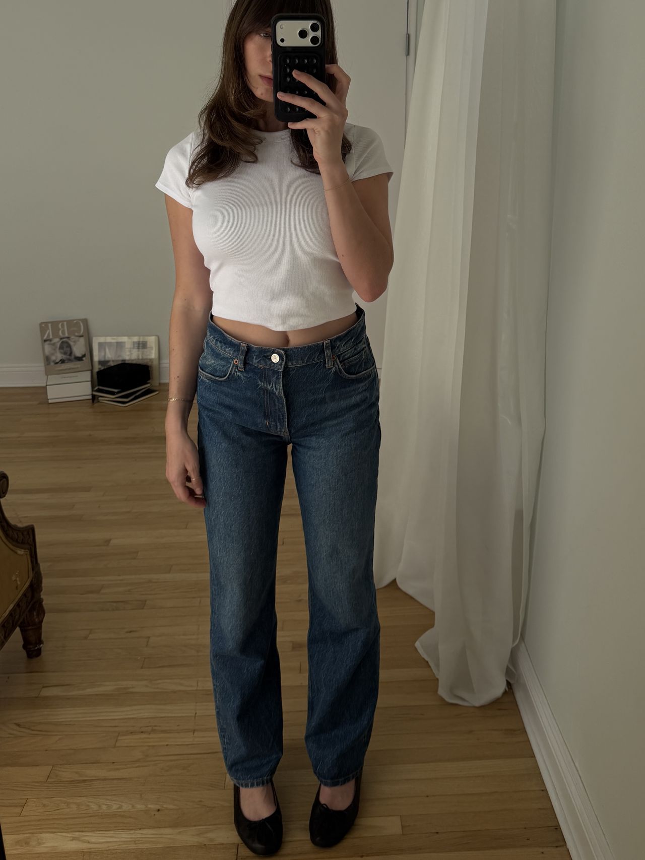 Kathryn Zahorak posing in mirror wearing white t-shirt, jeans, and black ballet flats
