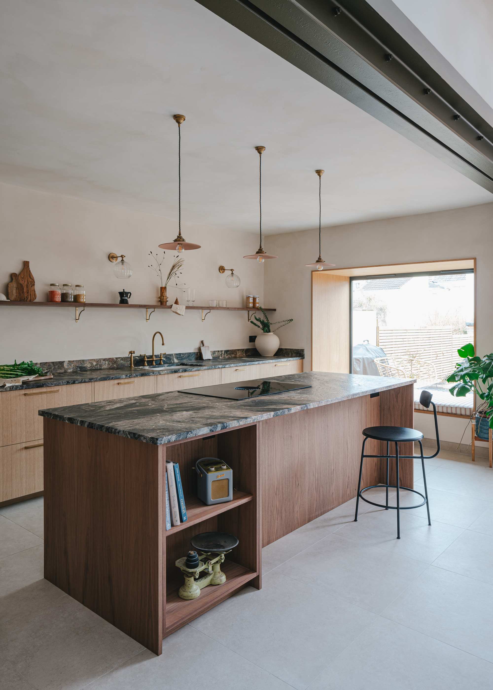 A modern kitchen with a large island, wooden base units, and a marble effect countertop