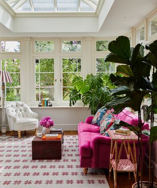 orangery with a roof lantern with bright pink sofa and white chair