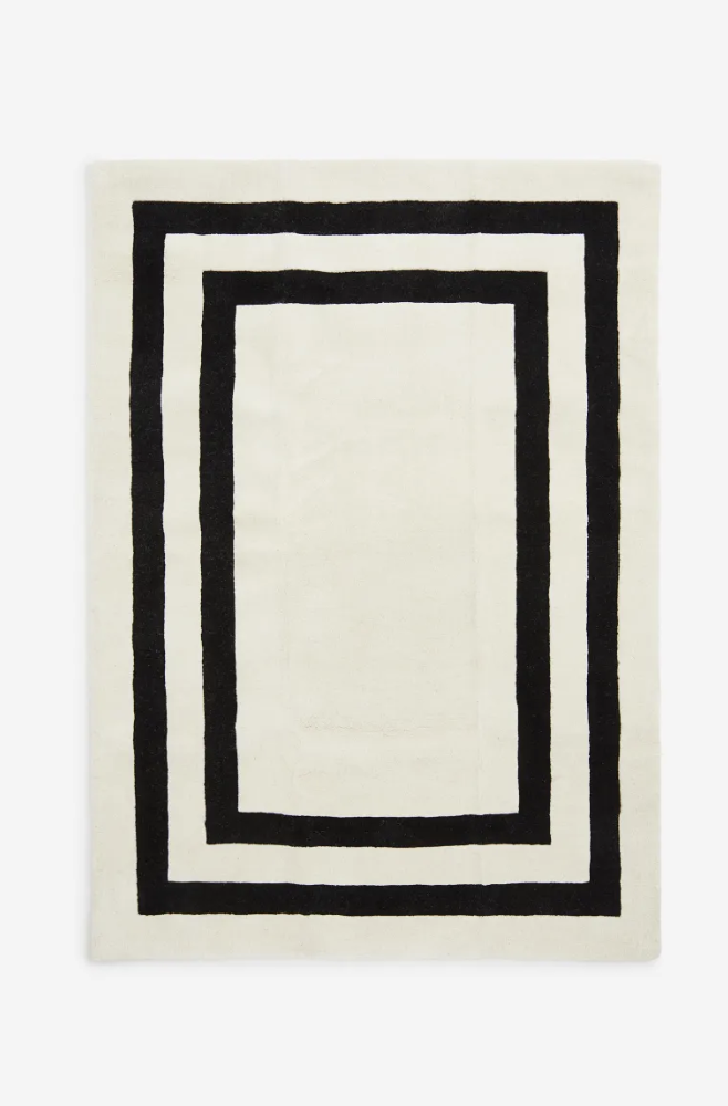 White tufted wool area rug with black accent border from H&M Home.