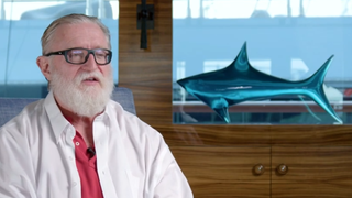 Gabe Newell speaking next to a shark.