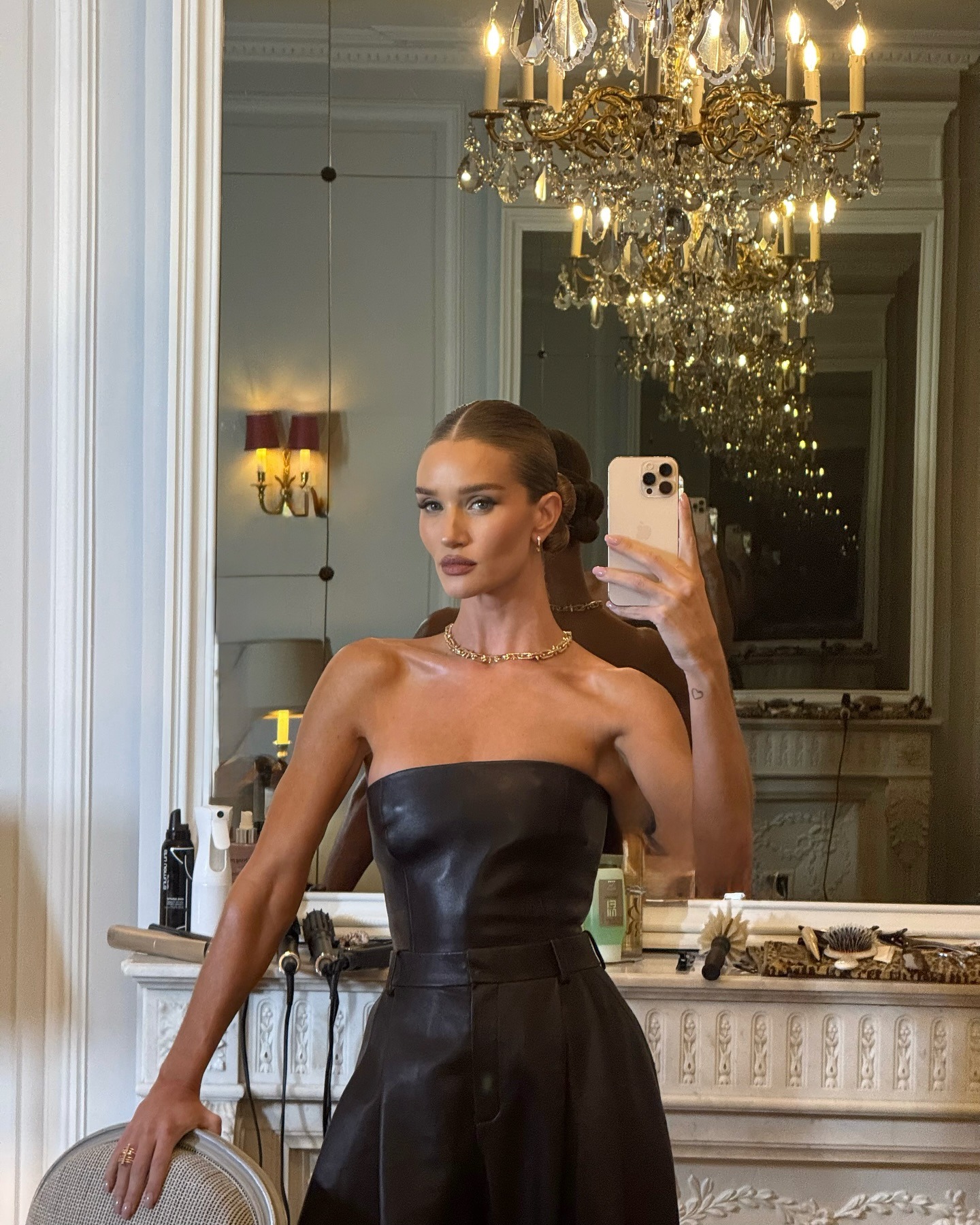 A picture of Rosie Huntington-Whiteley taking a mirror selfie in a leather dress wearing a gold necklace