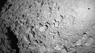 The Mobile Asteroid Surface Scout (MASCOT) lander captured this photo of asteroid Ryugu during its descent toward the space rock on Oct. 2, 2018. MASCOT’s shadow is visible at upper right.