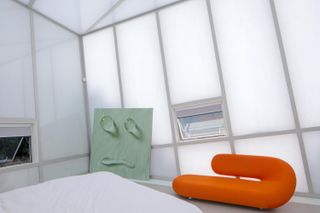 Bedroom with orange curved couch and white glazing at Maison de Verre, Studio Odile Decq