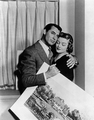 cary grant hugs myrna loy as he holds a painting in the movie mr blandings