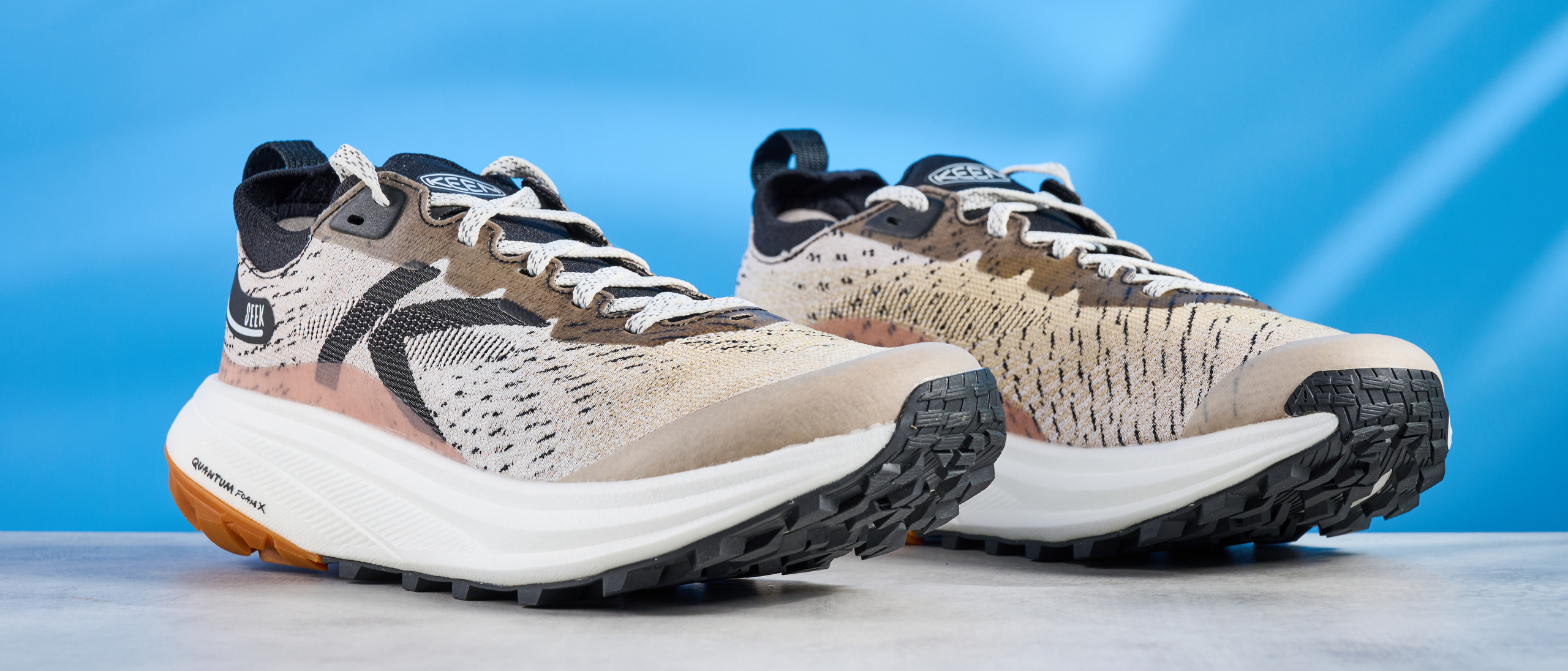 the keen seek trail shoes in brown, black, and beige photographed against the blue tom's guide background