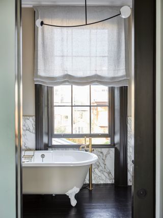 Elegant bathroom with freestanding bath and linen roman blind
