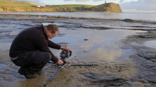 photographer by water's edge with low-level tripod