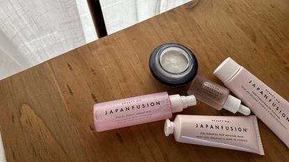 Beauty Pie Japan Fusion skincare products laid out on a wooden table