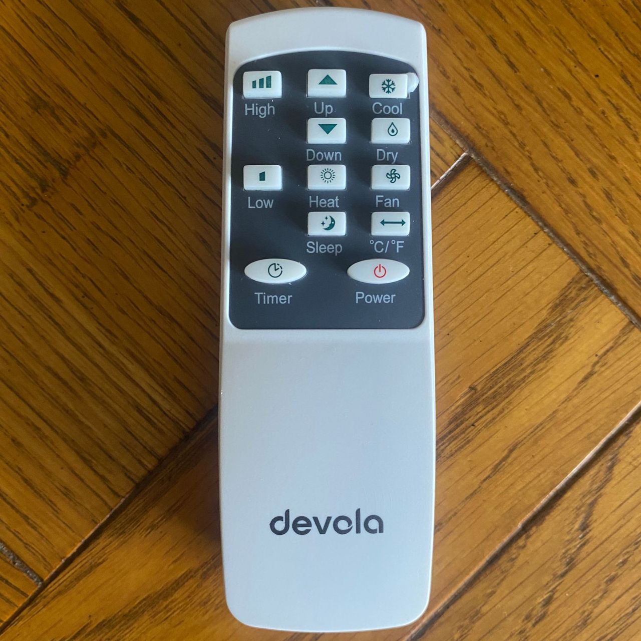 Remote control of the Devola DVAC09CW portable air conditioner on a wooden desk