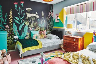 Kids' room with twin beds, black floral wallpaper, geometric colour block paint in green and yellow, and pink carpet