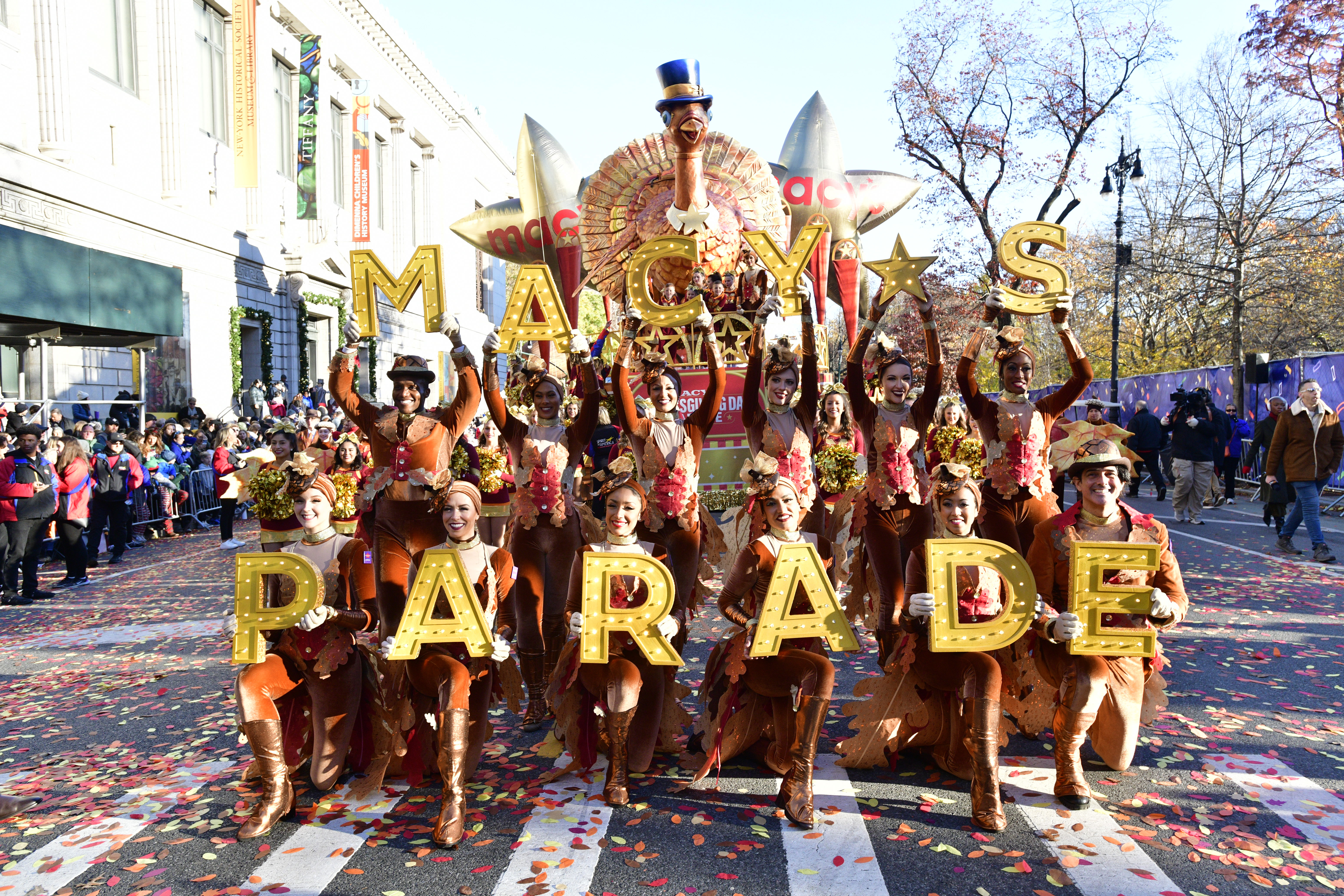 dancers hold up letters that spell out macys parade during the thanksgiving day parade