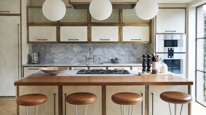 A retro style kitchen with brown island stool, cabinets, and white overhead lights