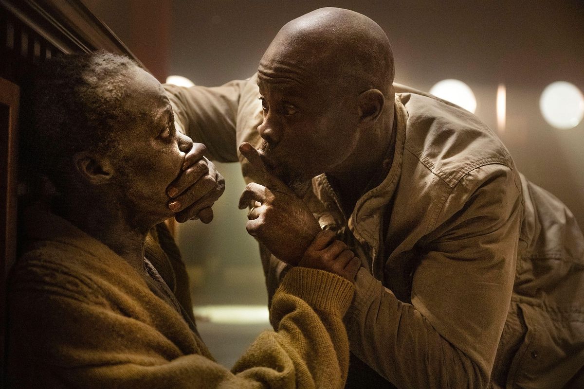 Henri (Djimon Hounsou) covers the mouth of Sam (Lupita Nyong&#039;o) and signals her to be quiet in the aftermath of the alien invasion in A Quiet Place Day One.