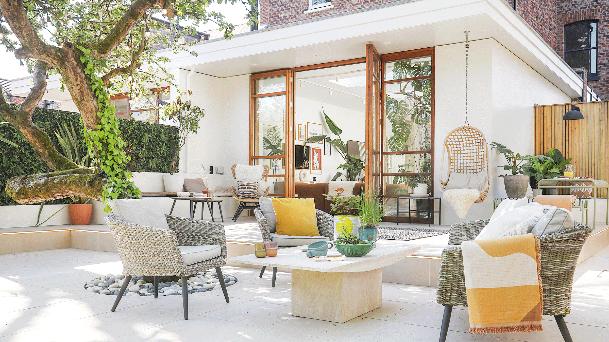 a patio area of a garden that leads into the rear of a house with bifold doors