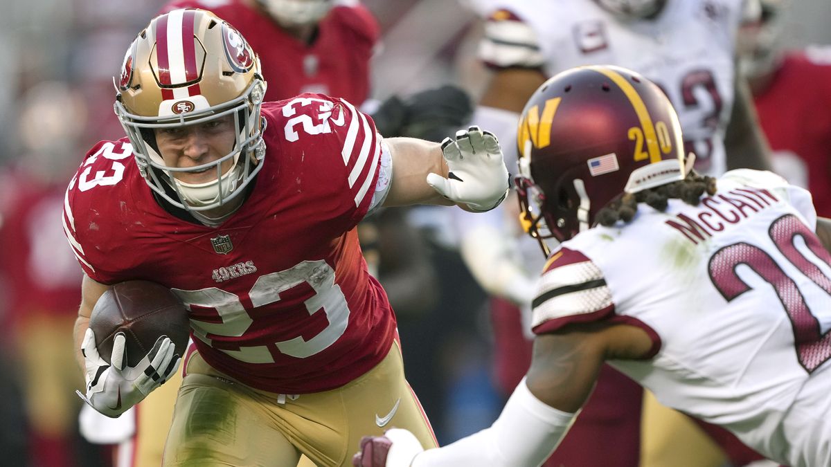 Christian McCaffrey (L) hands off a Washington player ahead of the 49ers vs Commanders live stream