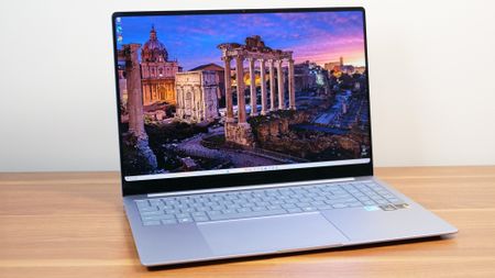 Samsung Galaxy Book 4 Edge angled on a wooden table with a sunset image on the display.