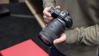 Canon RF 135mm f/1.8L IS USM lens being held in someone's hands on a Canon EOS camera