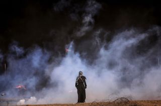 A person stands in front of a cloud of smoke