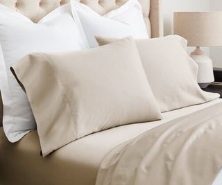 Gold and white sheets and pillows on a bed.