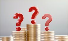 Red question marks on coin stacks before a defocused background. 