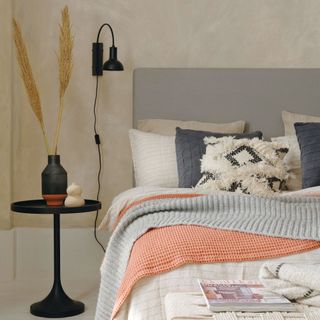 Neutral bed with orange and blue bedding on