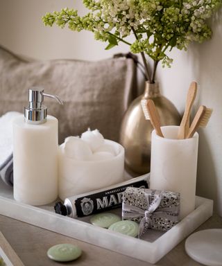 A close up shot of a tray holding candles, toothbrushes and toiletries