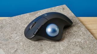 A black Logitech Ergo M575 ergonomic mouse with a teal trackball on the left side