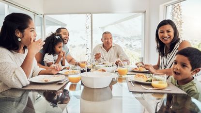 A multigenerational family talks and laughs over dinner.