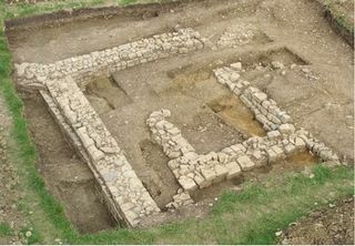 A bird's-eye view of the site showing the remains of the chapel's walls, the outer ones being a later addition. Archaeologists found graves under and outside of the chapels, including the four graves that are visible in this photo.