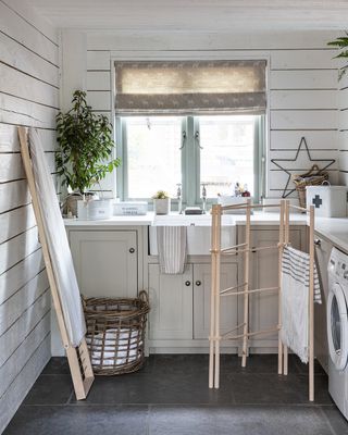 Cream shaker style kitchen units, with Belfast sink, washing machine and wooden laundry accessories in a utility room