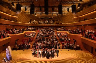 The L-Acoustic team welcomes its 1,000th member in a concert hall.