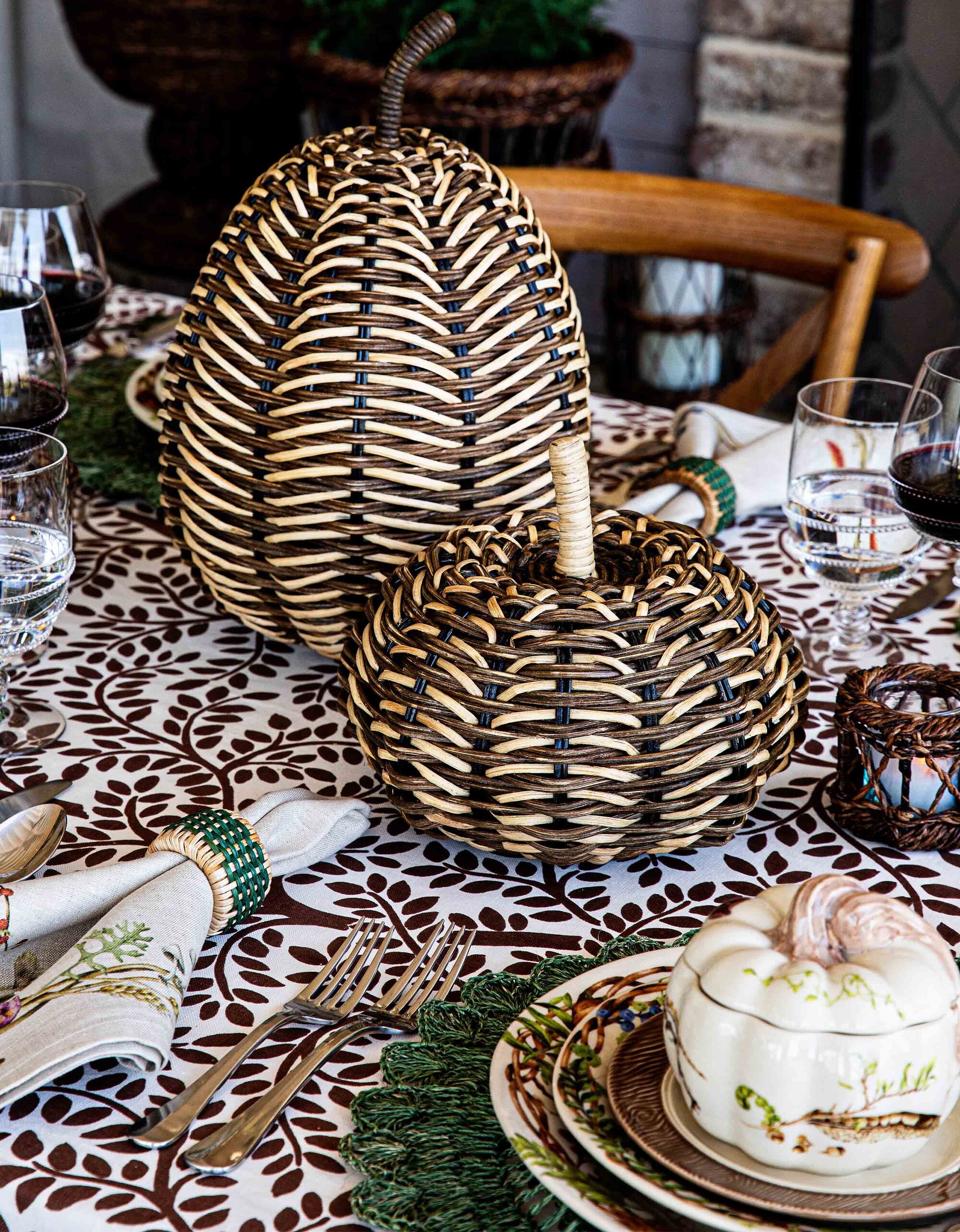 Image of a fall-themed table setting with wicker pumpkins in the center. There are other tactile details like rattan napkin rings and textured placemats.