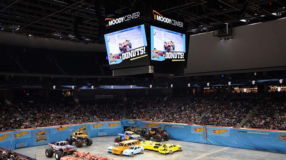 A colorful Daktronics LED videoboard hangs from the ceiling of the Moody Center in Austin, TX.