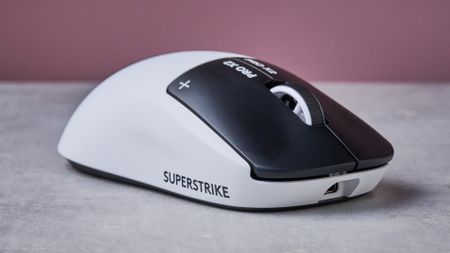 Three-quarter view of Logitech G Pro X2 Superstrike on white desk with pink wall in background