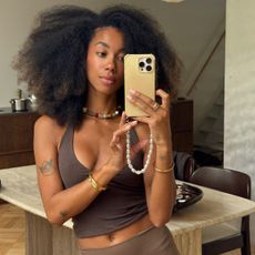 A woman taking a mirror picture with small tattoos on her arms