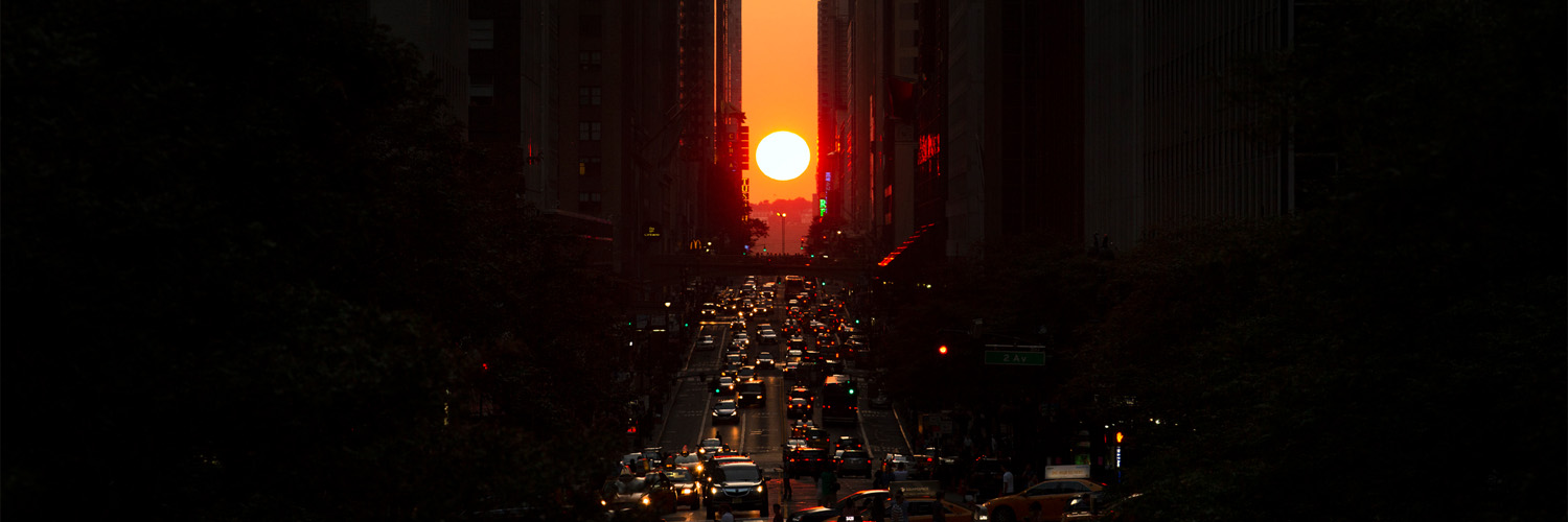 sun setting between buildings in manhattan